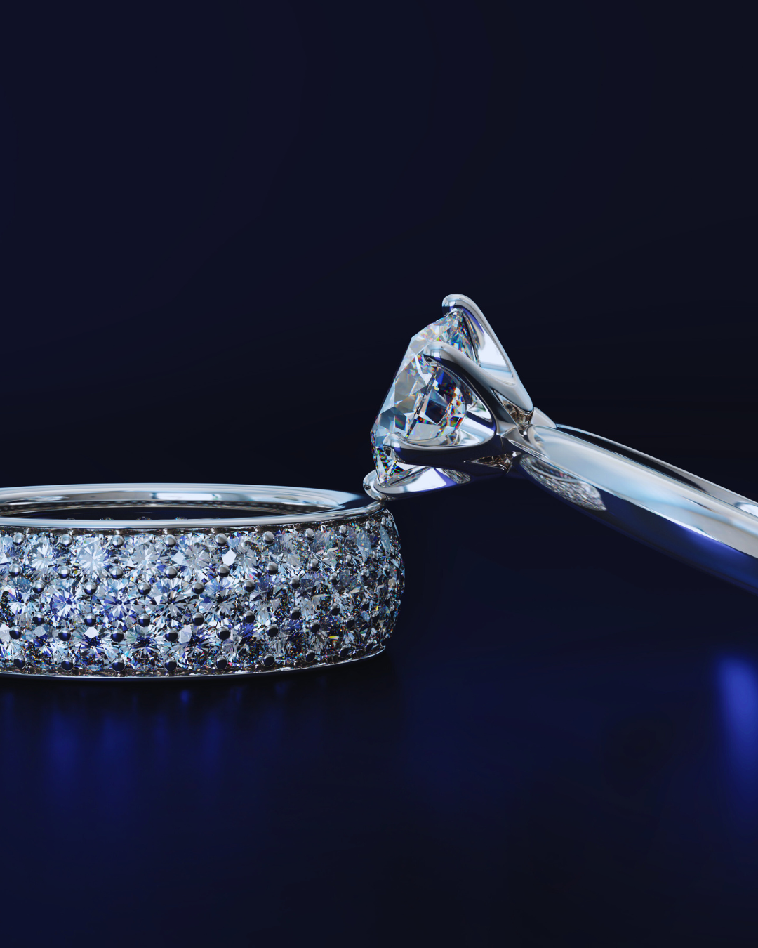 Primo piano di un anello solitario con grande diamante rotondo e una veretta a fascia larga interamente ricoperta di diamanti pavé, su sfondo blu scuro. Gioielli di lusso Atelier Diamanti per fidanzamento e matrimonio.