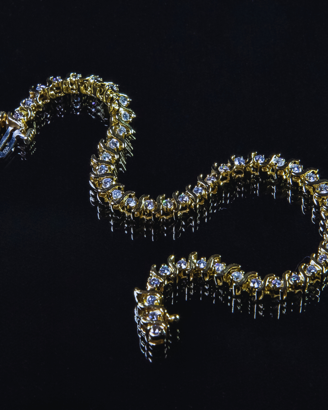 Elegante bracciale tennis in oro giallo con una fila continua di diamanti scintillanti, posizionato su una superficie scura riflettente. Gioiello di lusso e raffinatezza di Atelier Diamanti, ideale per ogni donna a Roma.