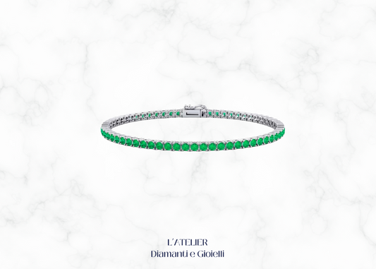 Bracciale tennis con smeraldi verdi e altre pietre preziose, su sfondo scuro. Gioiello di lusso con smeraldi di Atelier Diamanti e Gioielli